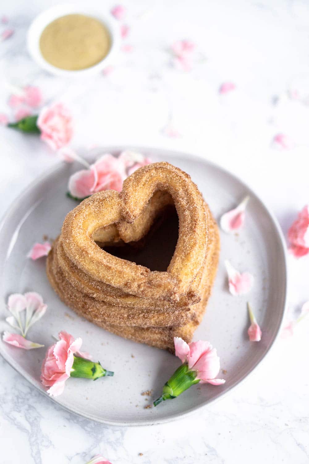 heart shaped churros stacked on a plate with pink flowers