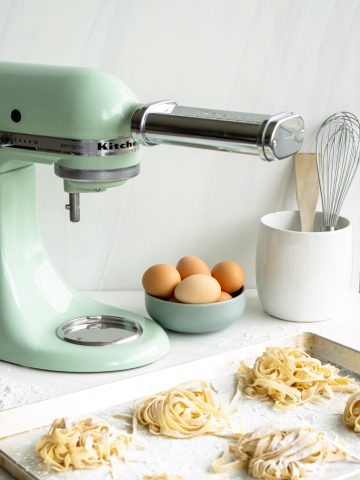 KitchenAid mixer with pasta attachment with homemade pasta in the foreground