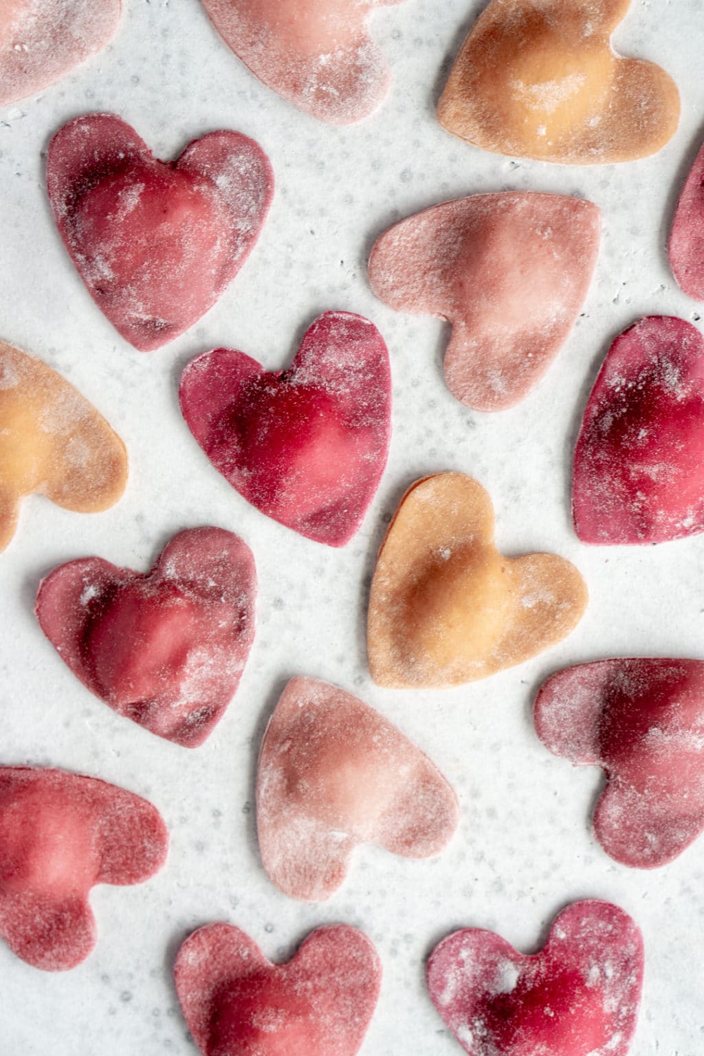 overhead shot of heart ravioli scattered on a white surface