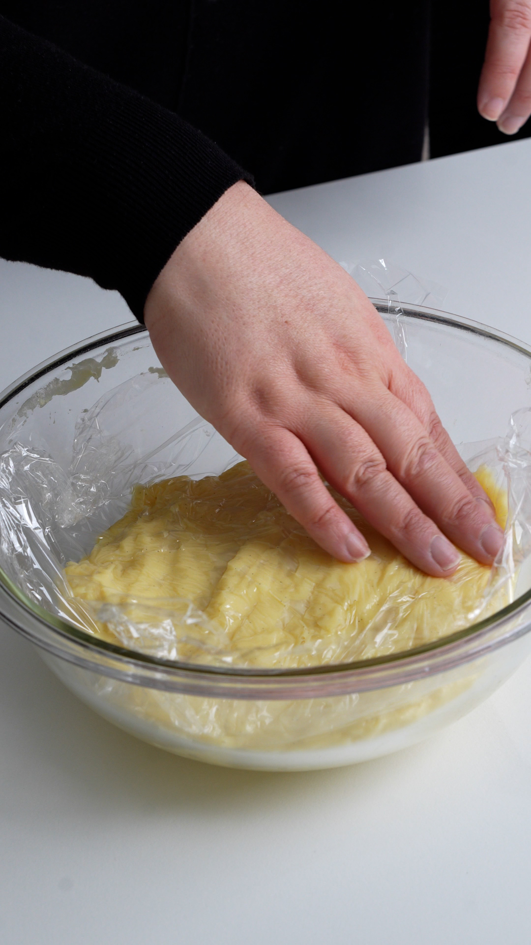 Pastry cream in a bowl topped with plastic wrap
