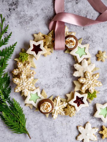 Holiday cookie wreath with greenery to one side and more cookies to the other side