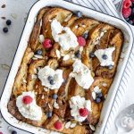 Panettone bread pudding in a baking dish topped with whipped cream and berries