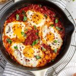Eggs in tomato sauce in a pan topped with basil
