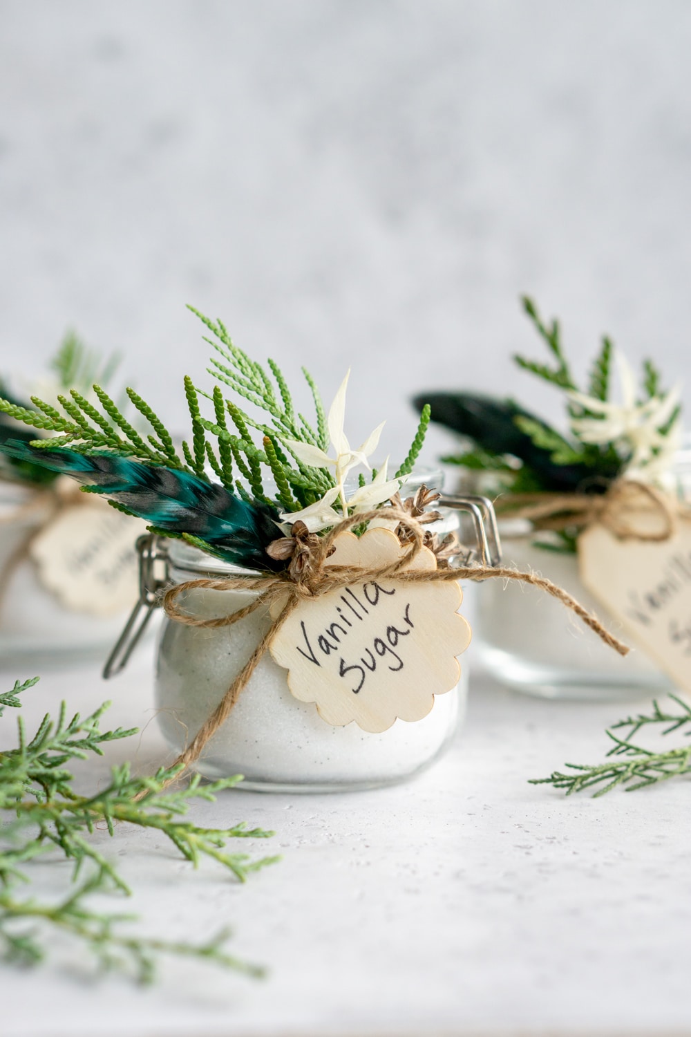 Three jars of vanilla sugar decorated with fresh greenery and tags