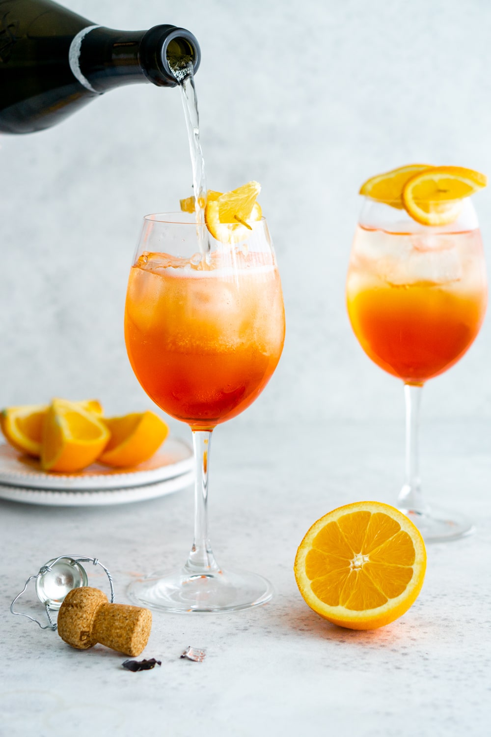 2 glasses of aperol spritz with prosecco being poured into one glass