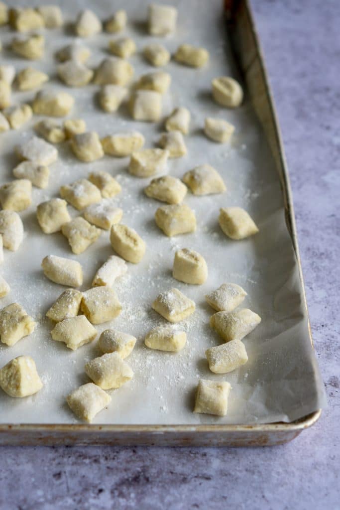 Front view of uncooked ricotta gnocchi on a baking tray dusted with flour