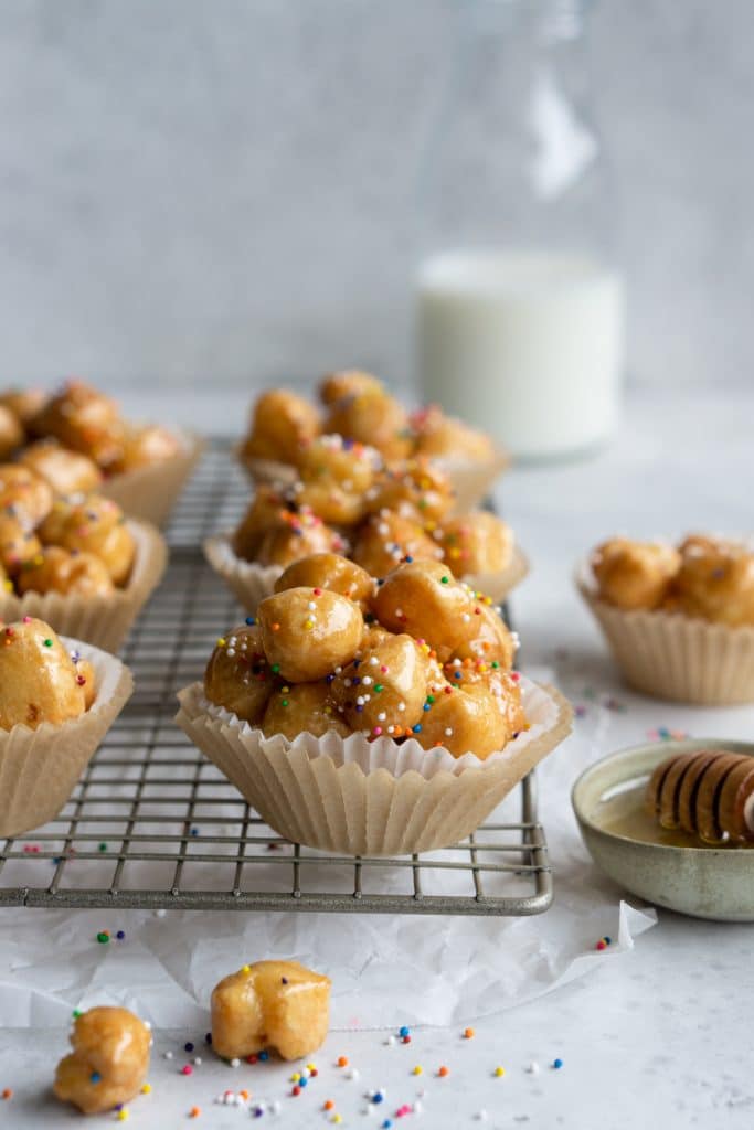 Struffoli in individual muffin liners with a bottle of milk in the background