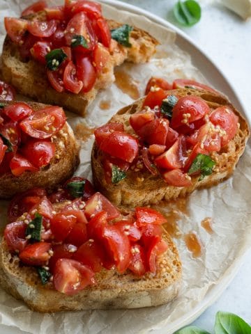 Tomato bruschetta on a plate, on top of parchment paper