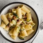 Zucchini and pancetta pasta in a bowl with a fork to the side
