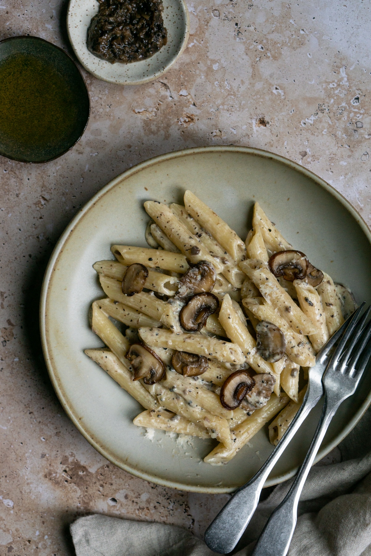 creamy mushroom pasta in a plate with two forks and a napkin too the side
