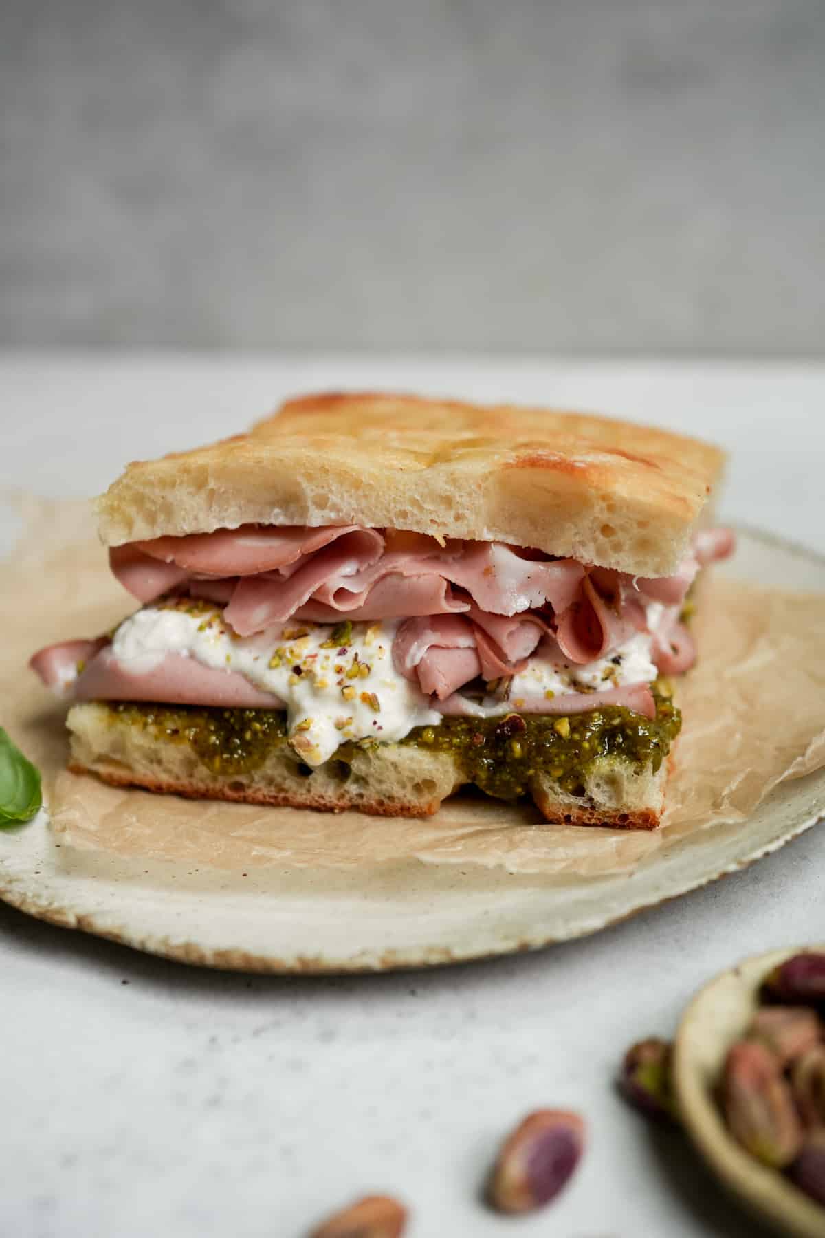 A mortadella sandwich with pistachio pesto and burrata on a plate