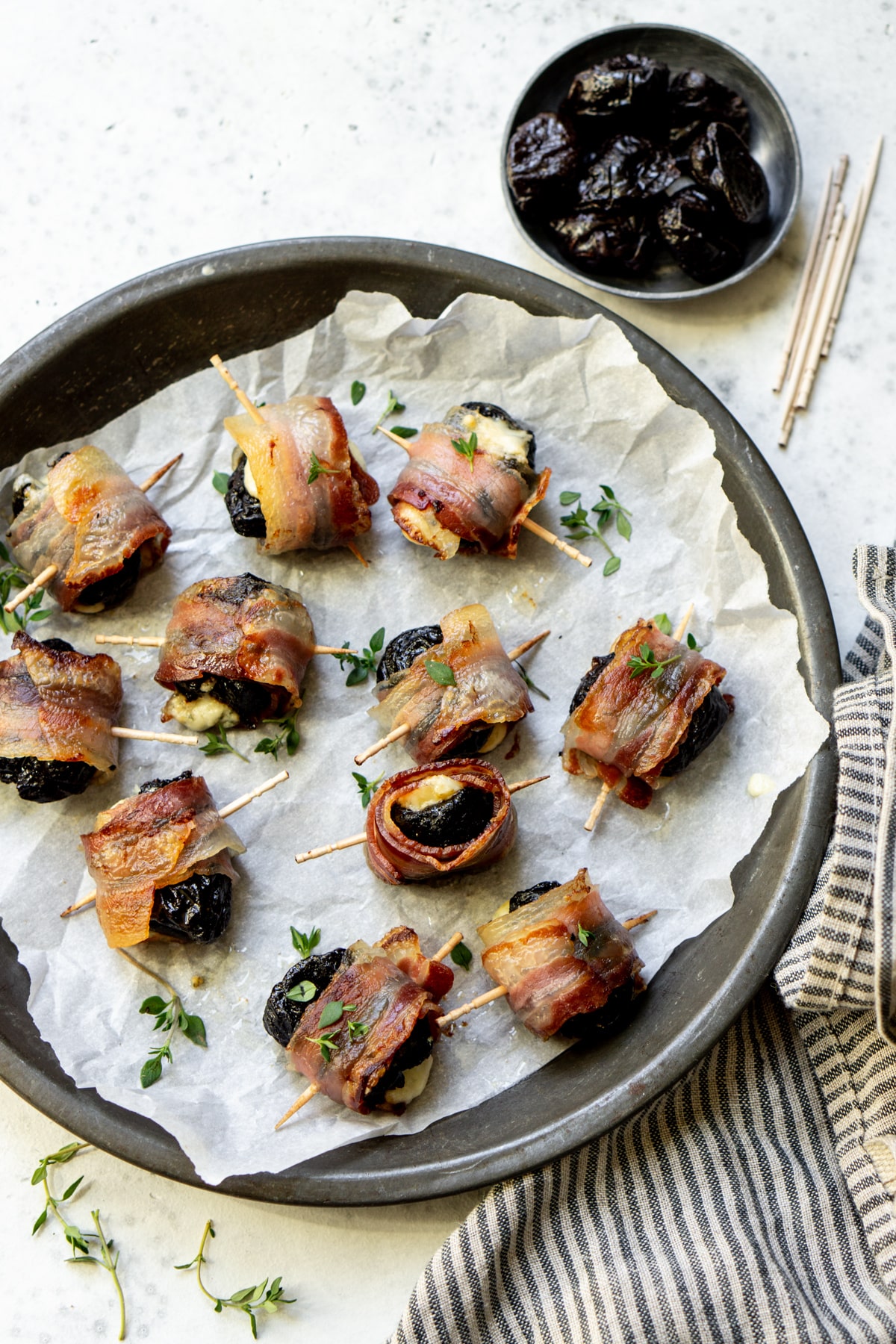 Stuffed prunes in a dish topped with fresh thyme
