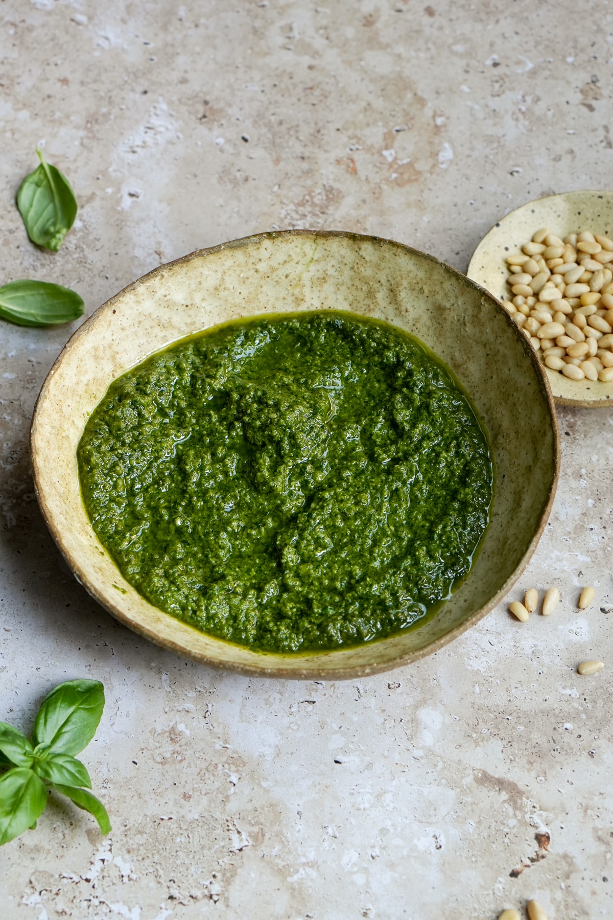Bowl of genovese pesto with fresh basil leaves to the side