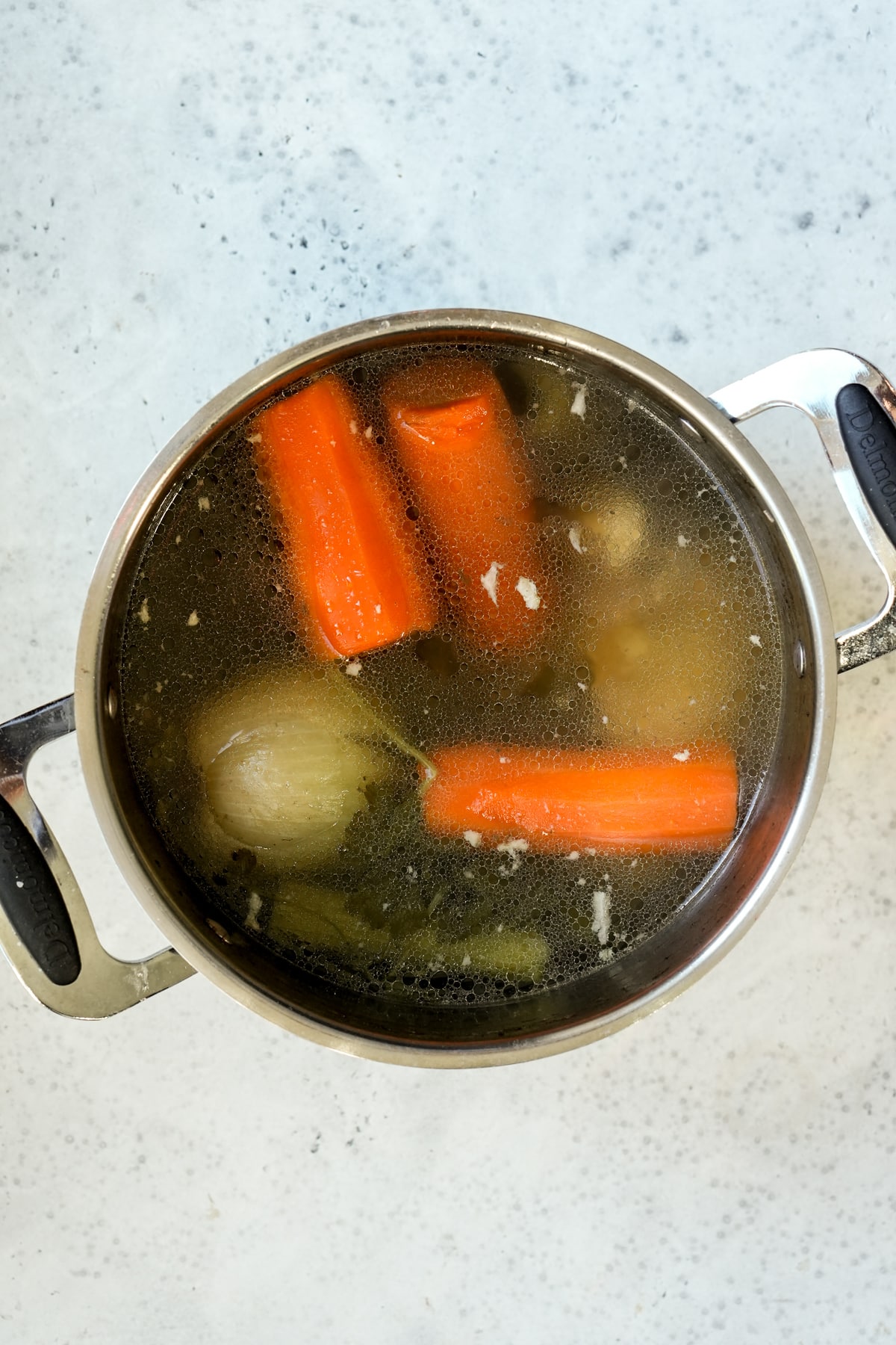 Italian brodo in a pot with carrots, onions, chicken and celery