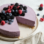 Berry mousse cake on a plate topped with fresh berries