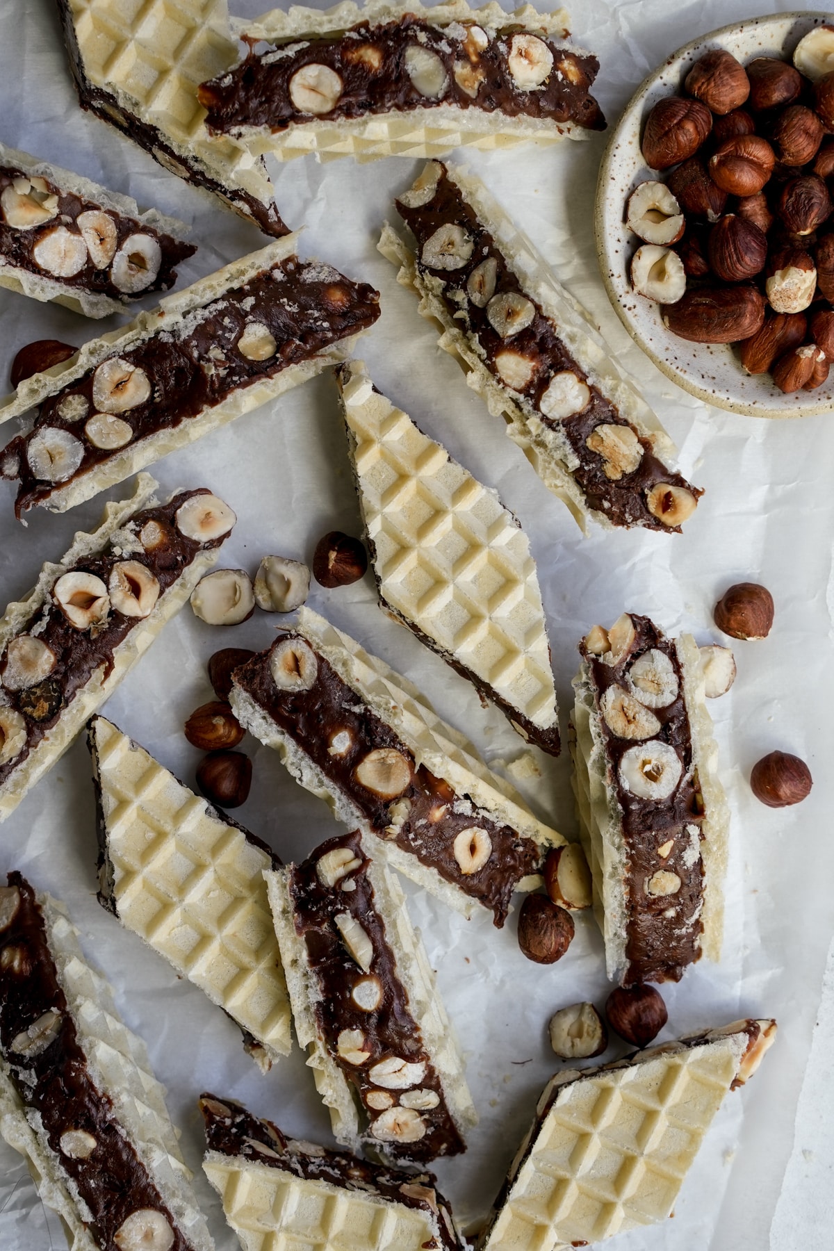 Marshmallow torrone on parchment paper with a small bowl of hazelnuts to the side