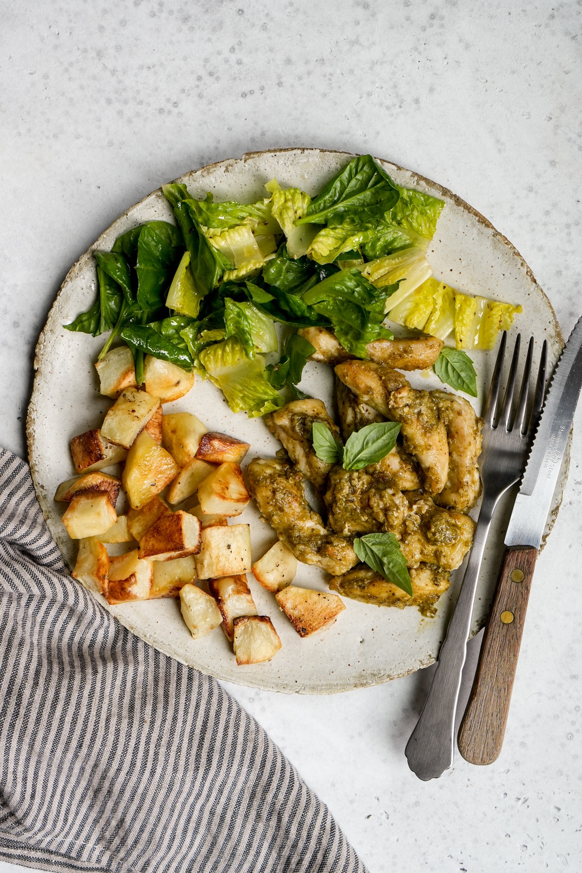 Italian pesto chicken on a dish with roasted potatoes and salad