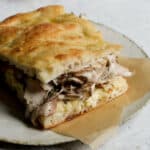 Porchetta sandwich with roasted potato cream and parmigiano cream on schiacciata bread