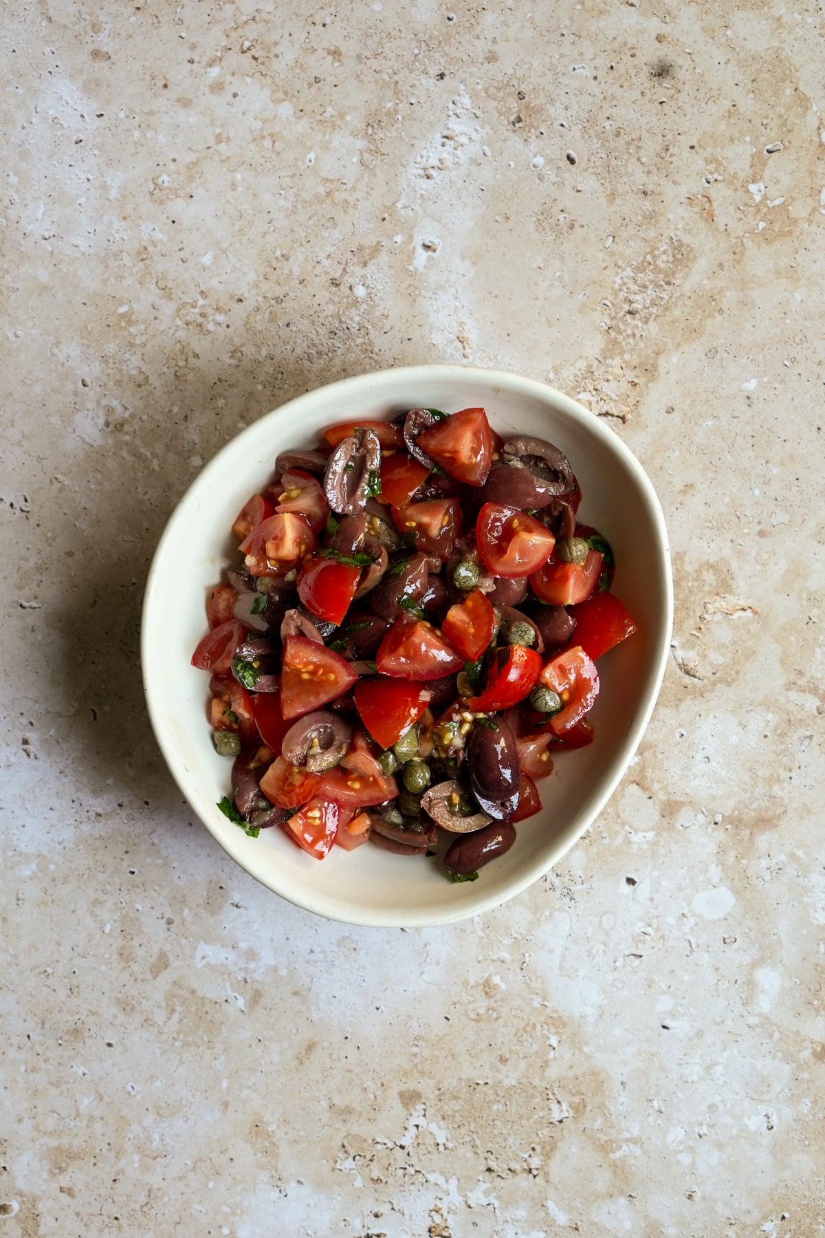 Tomatoes, olives, capers, garlic and parsley in a bowl