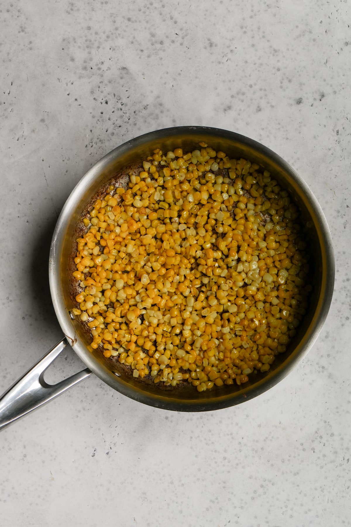 Italian farro salad process - sauteed corn kernels in a pan
