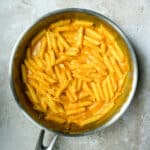 Penne pasta in a pan mixed with silky pumpkin pasta sauce
