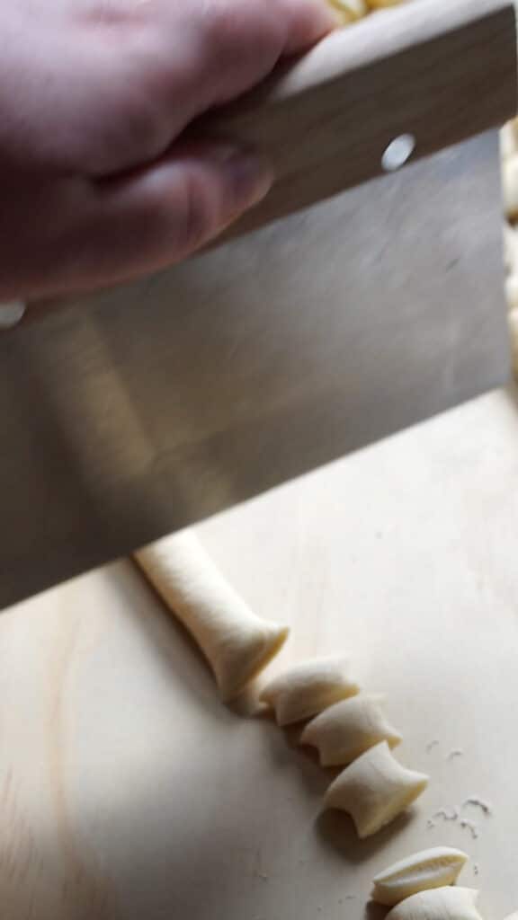 Dough being cut into small pieces with a bench scraper