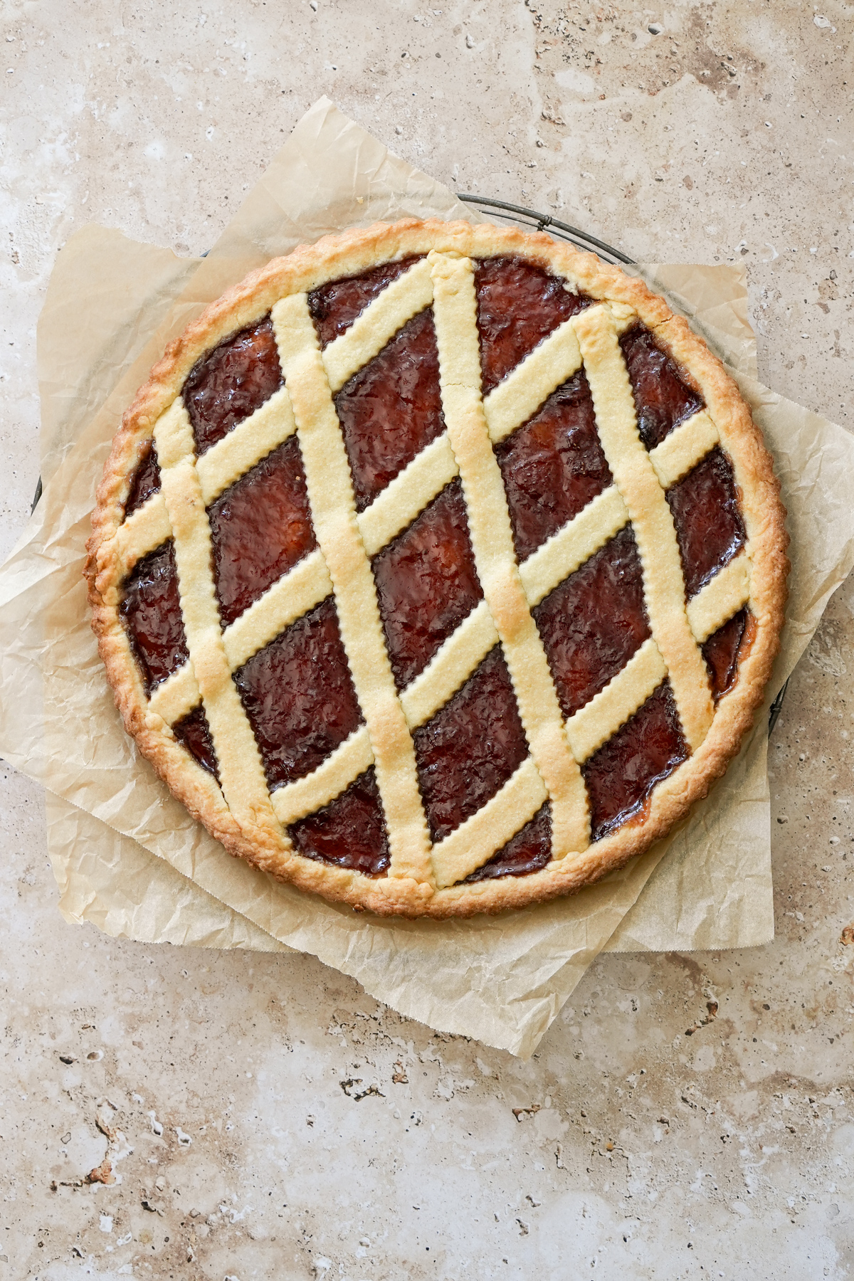 Whole crostata on a cooling rack with parchment paper