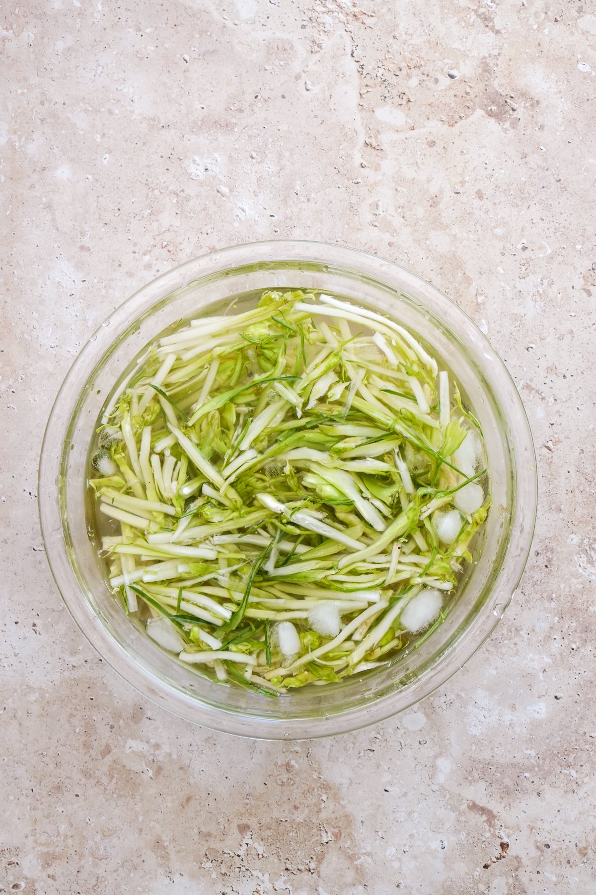 Julienned puntarelle in a glass bowl with water and ice