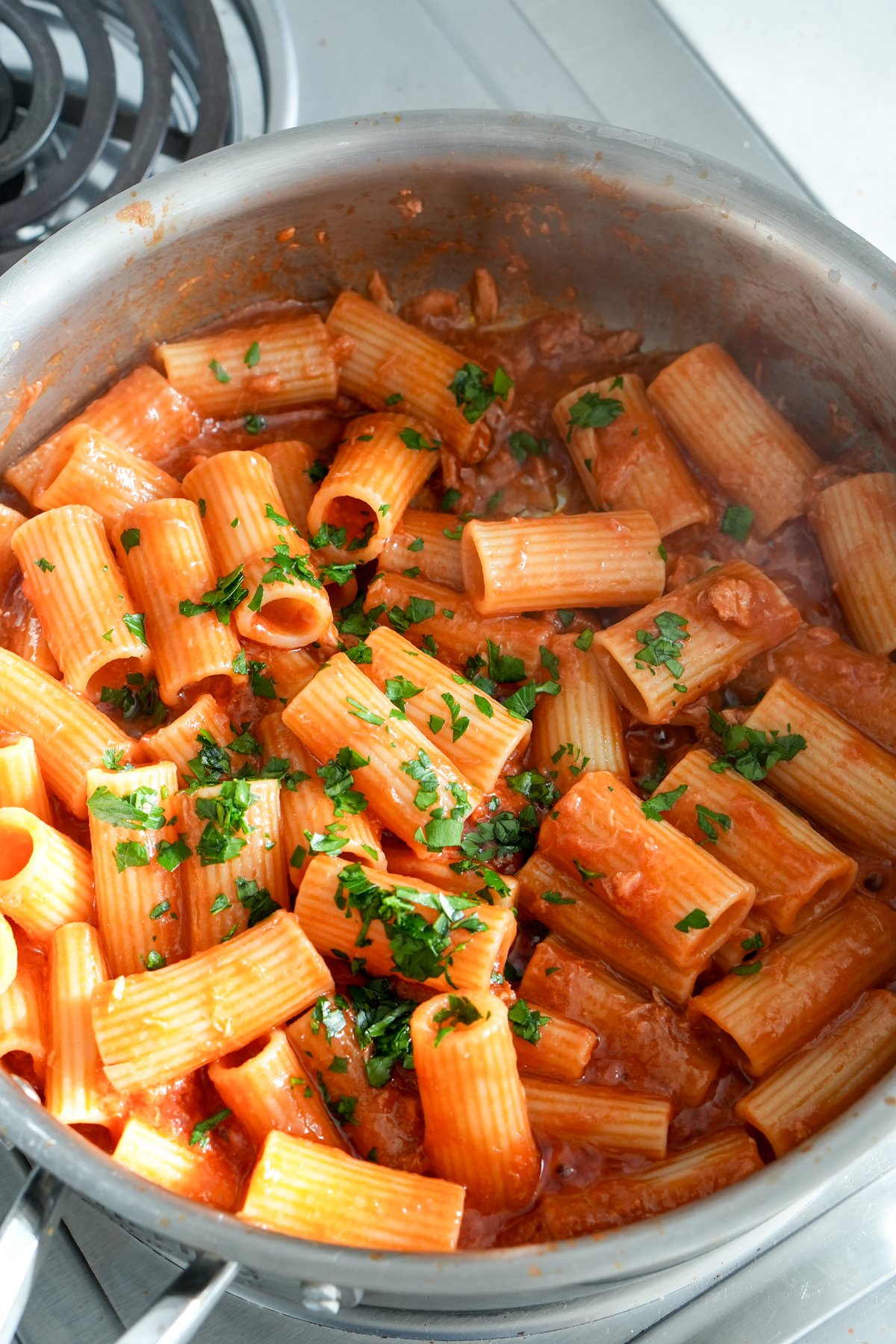 Rigatoni in canned tuna tomato sauce sprinkled with fresh parsley in a pan