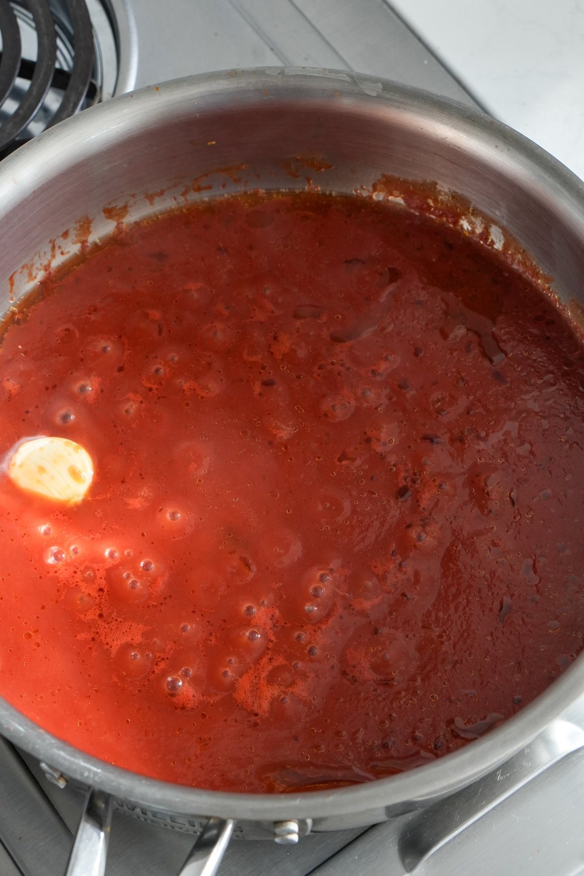 Tomato passata with a garlic clove in a pan on the stove