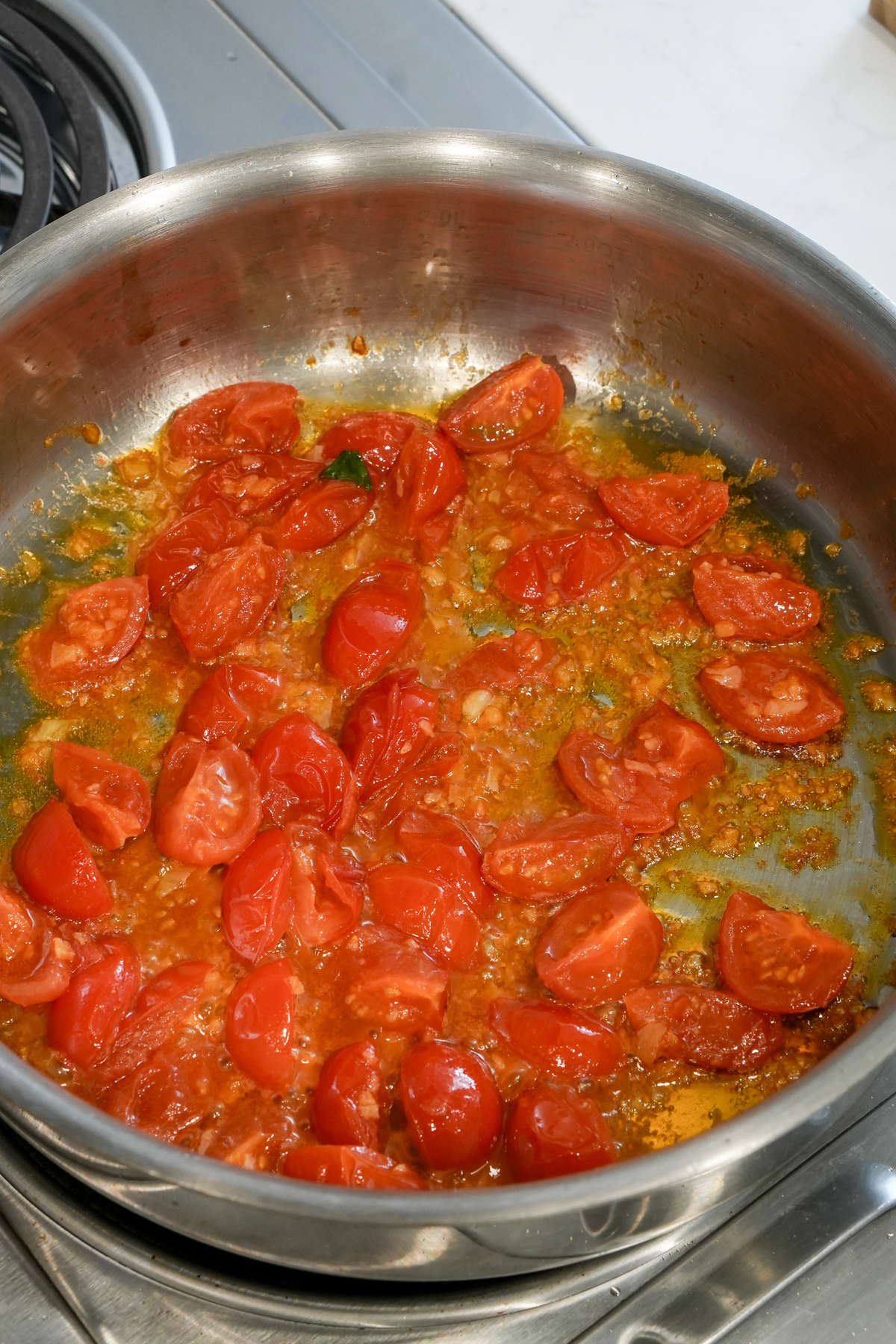cooked tomatoes in a pan with olive oil and garlic