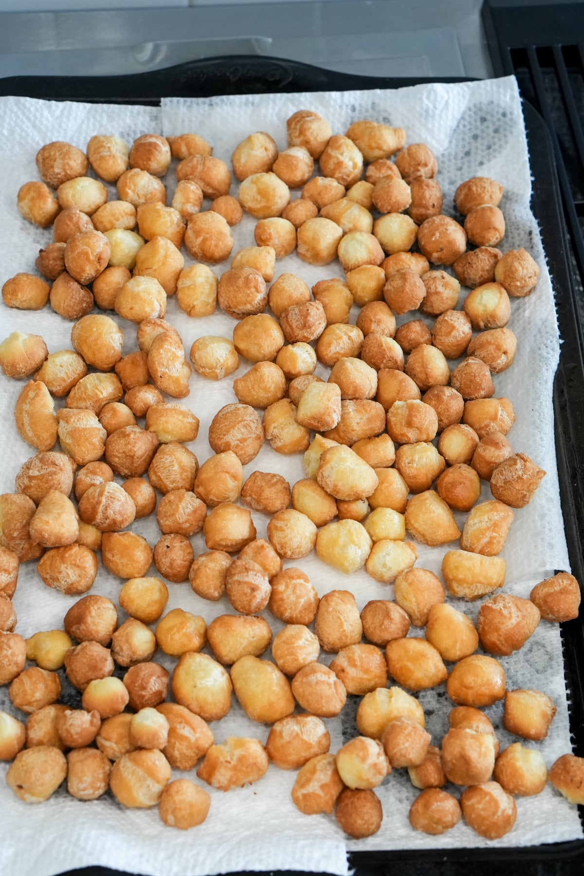 Freshly fried struffoli on a parchment-lined baking sheet