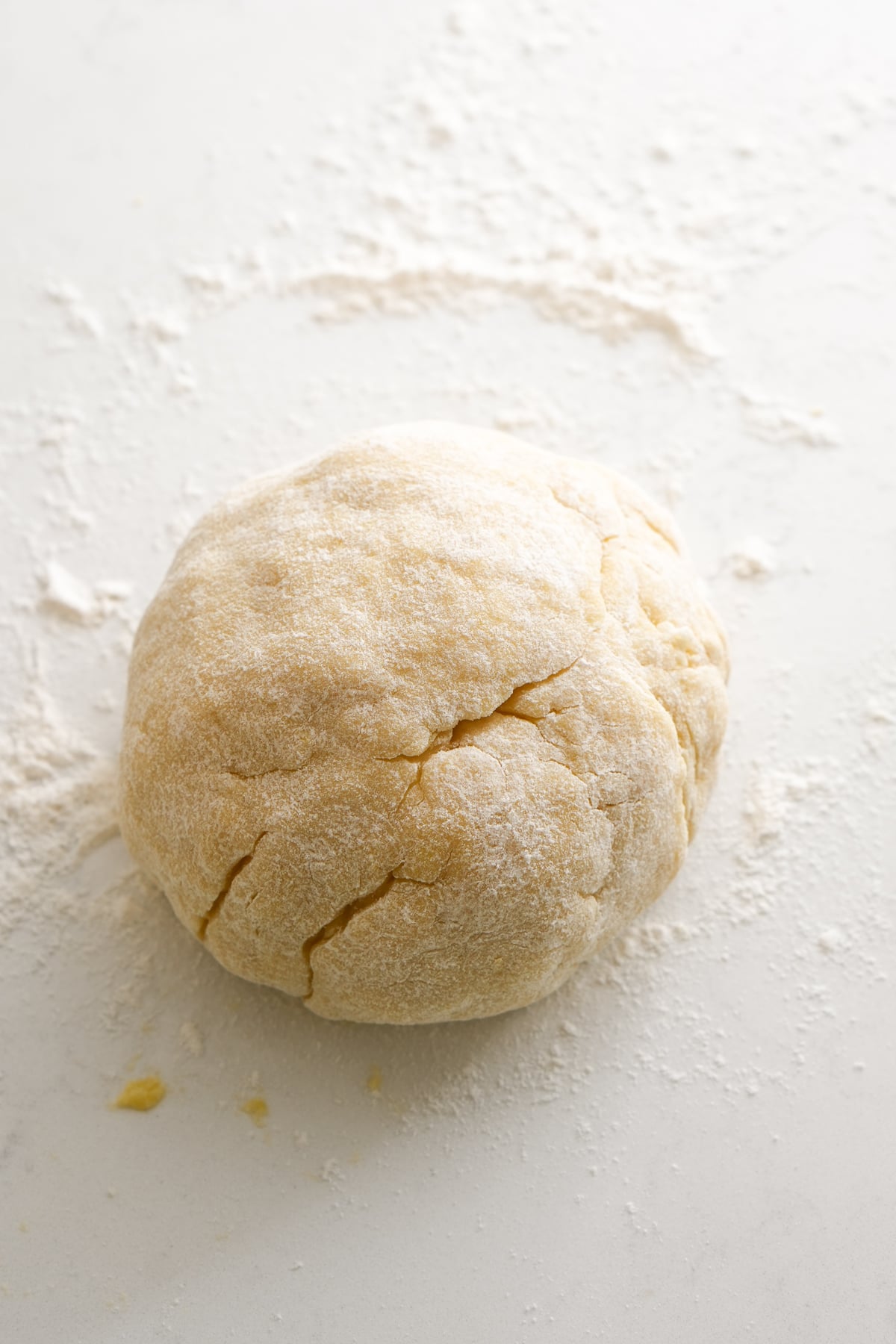 Ball of struffoli dough on a white surface