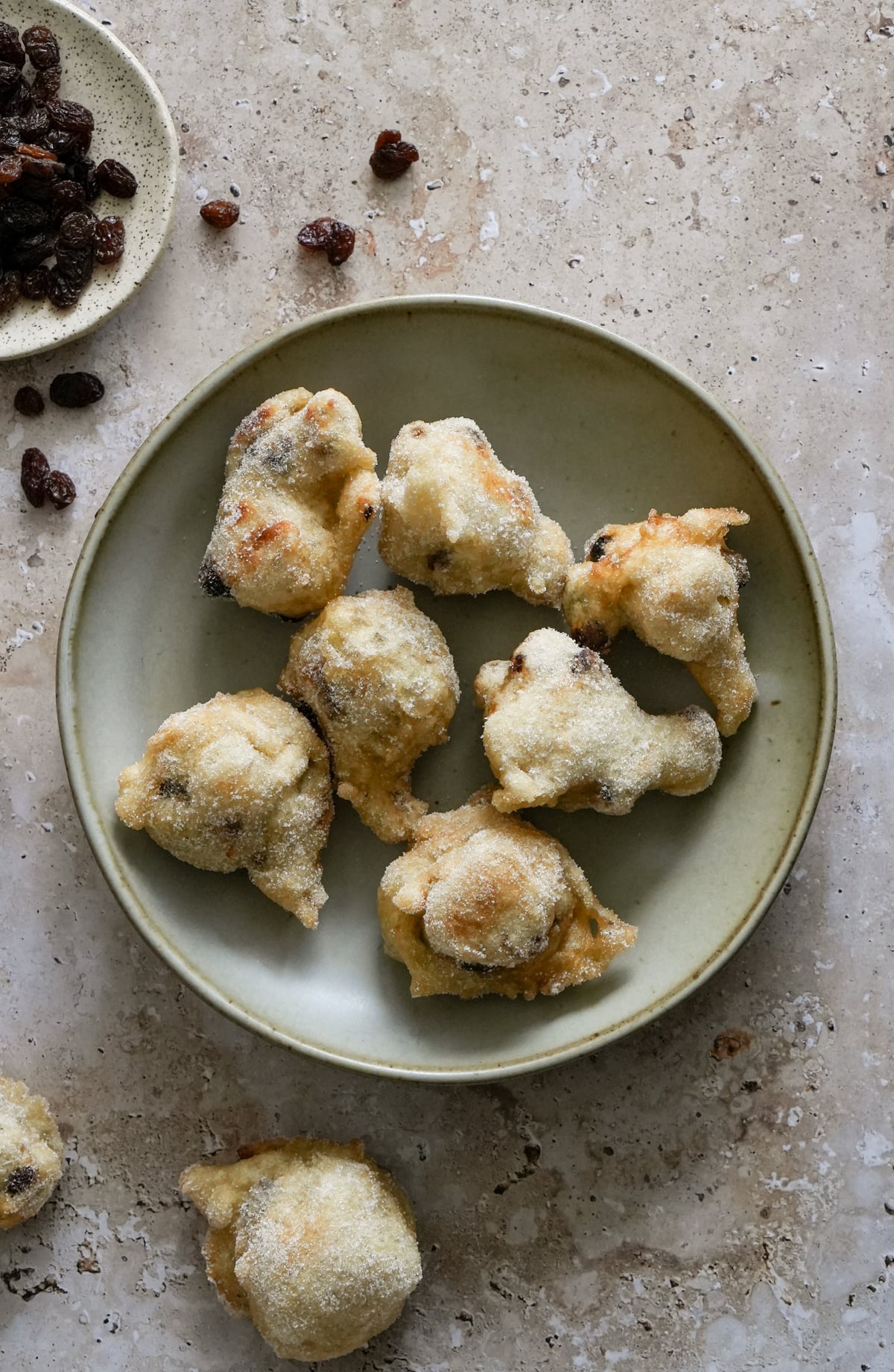 zeppole in a dish with a small plate of raisins to the side