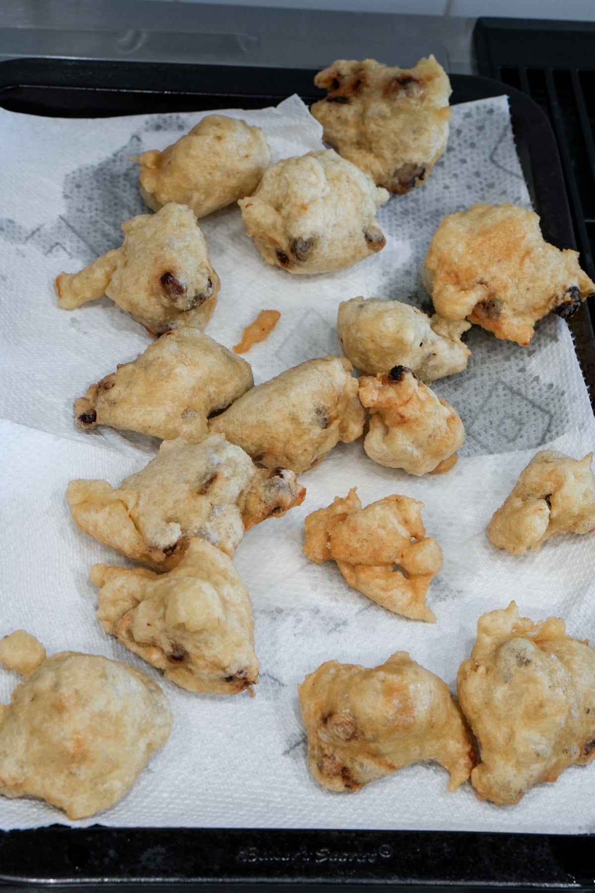 Fried zeppole on a paper towel-lined baking sheet