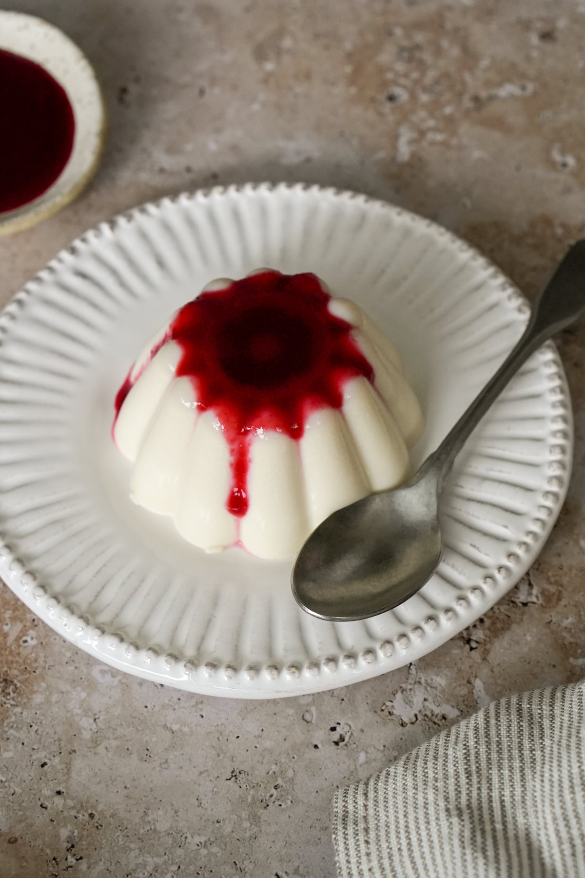 A serving of panna cotta in a dish topped with raspberry sauce