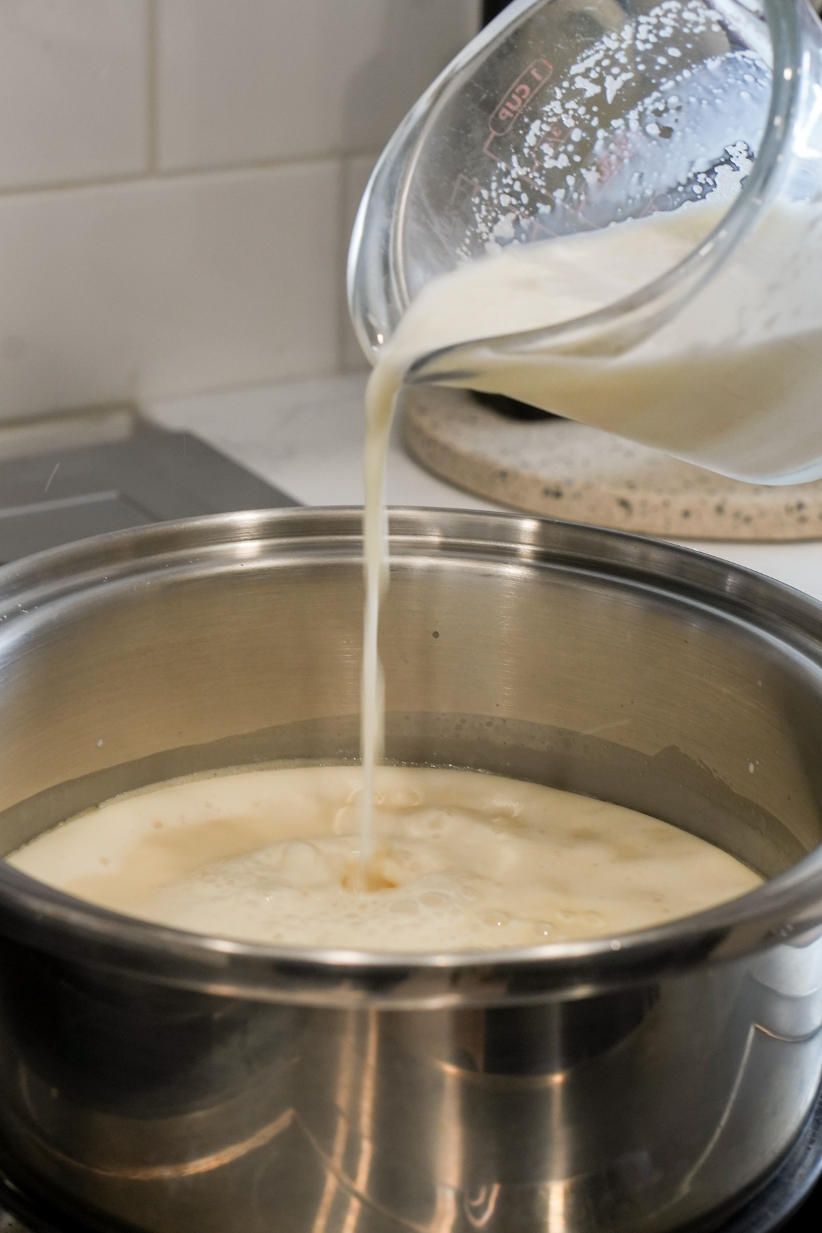 Pouring milk/gelatin mixture into a saucepan with whipping cream and sugar