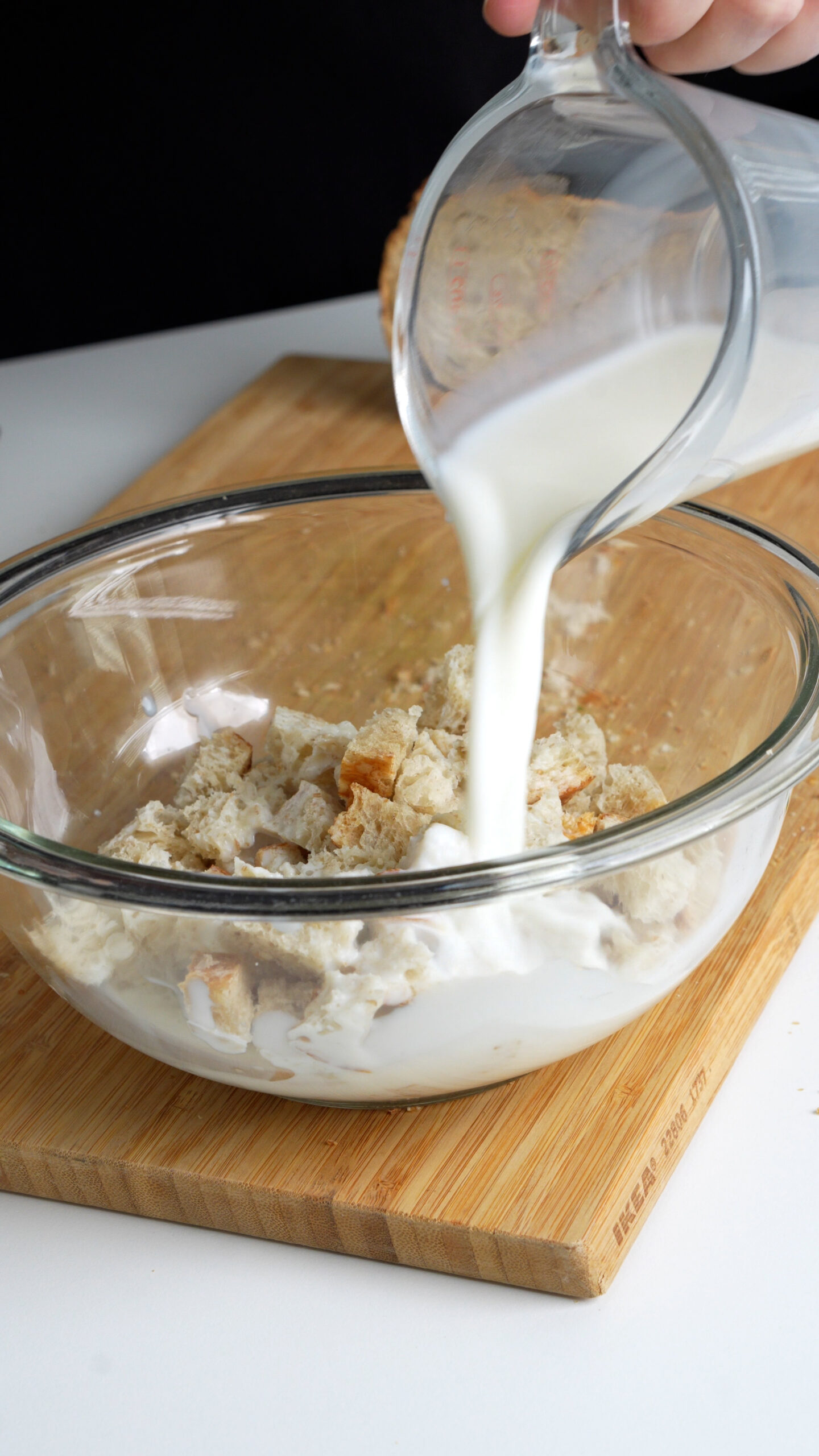 Cubed bread in a bowl with milk being poured on top