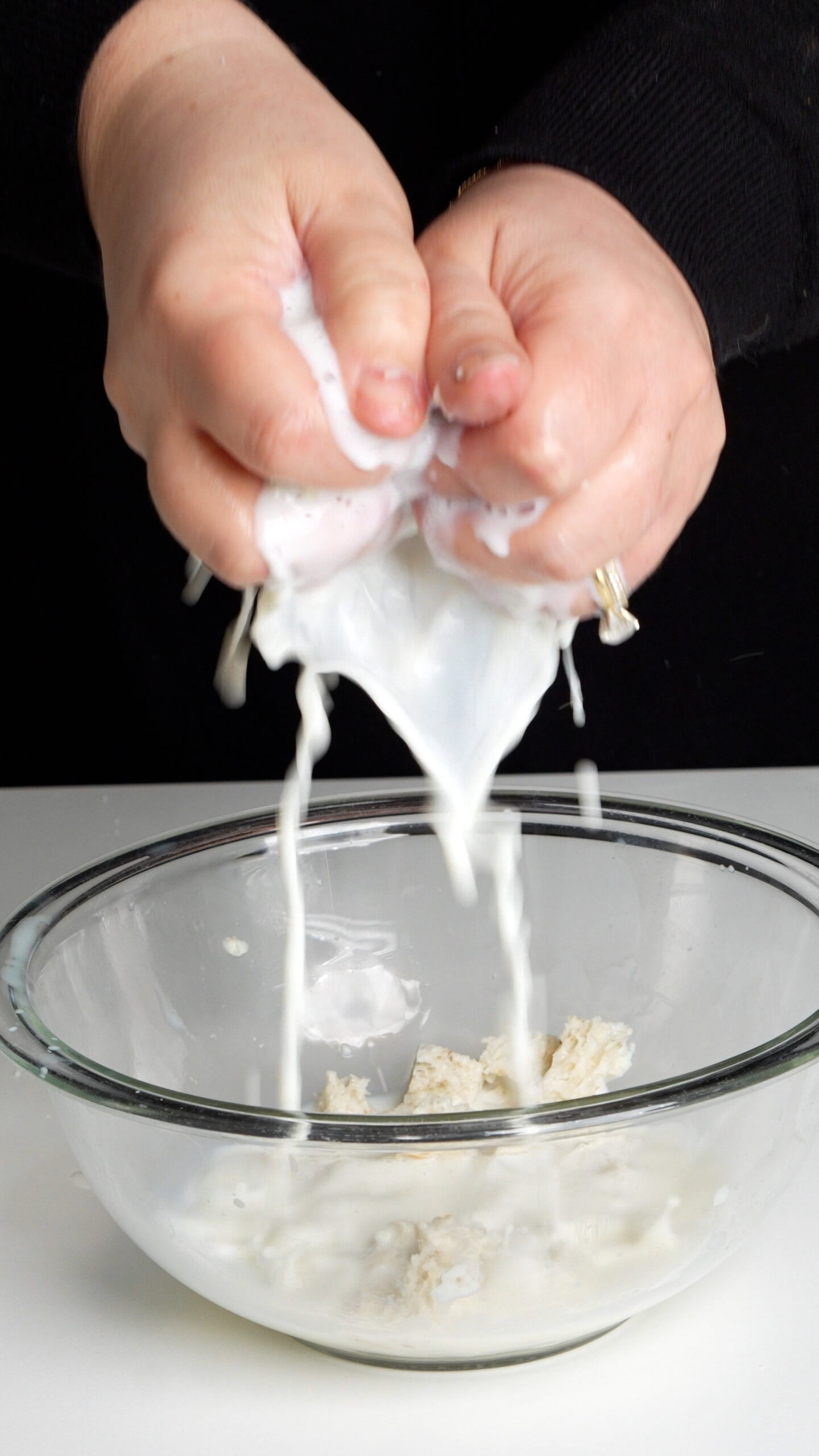 Milk being squeezed out of bread into a bowl