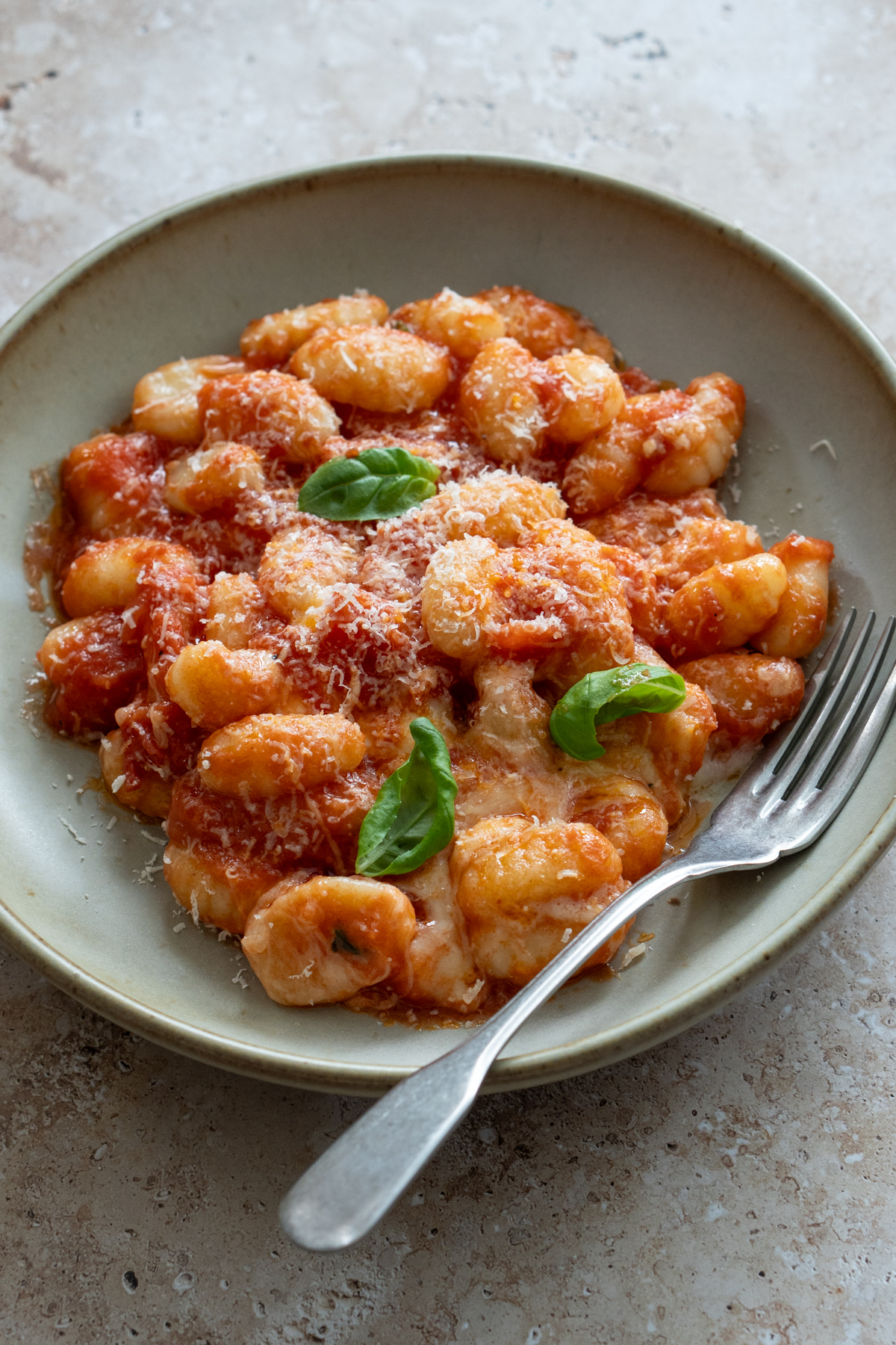 Gnocchi in a plate with tomato sauce toppd with grated parmigiano