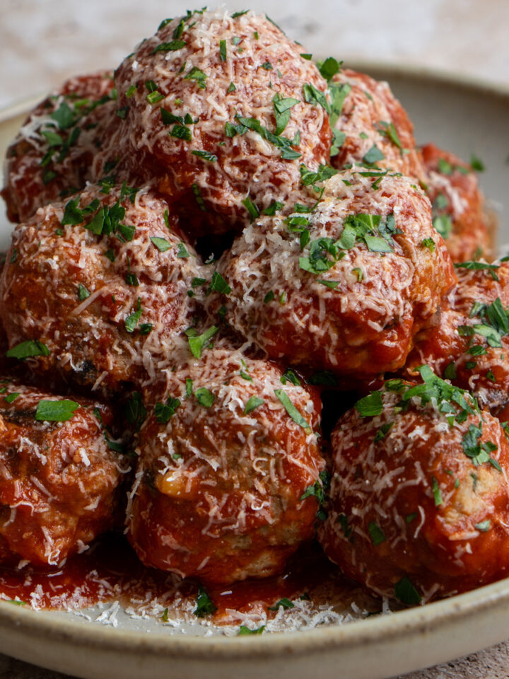 italian meatballs in a dish sprinkled with grated parmigiano and parsley