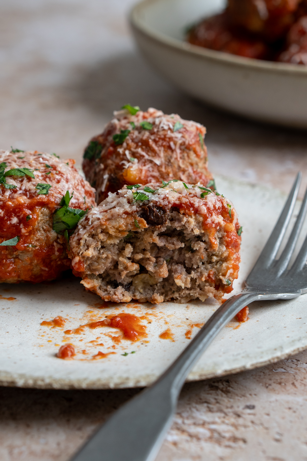 Meatballs in a plate with a piece taken out of one meatball