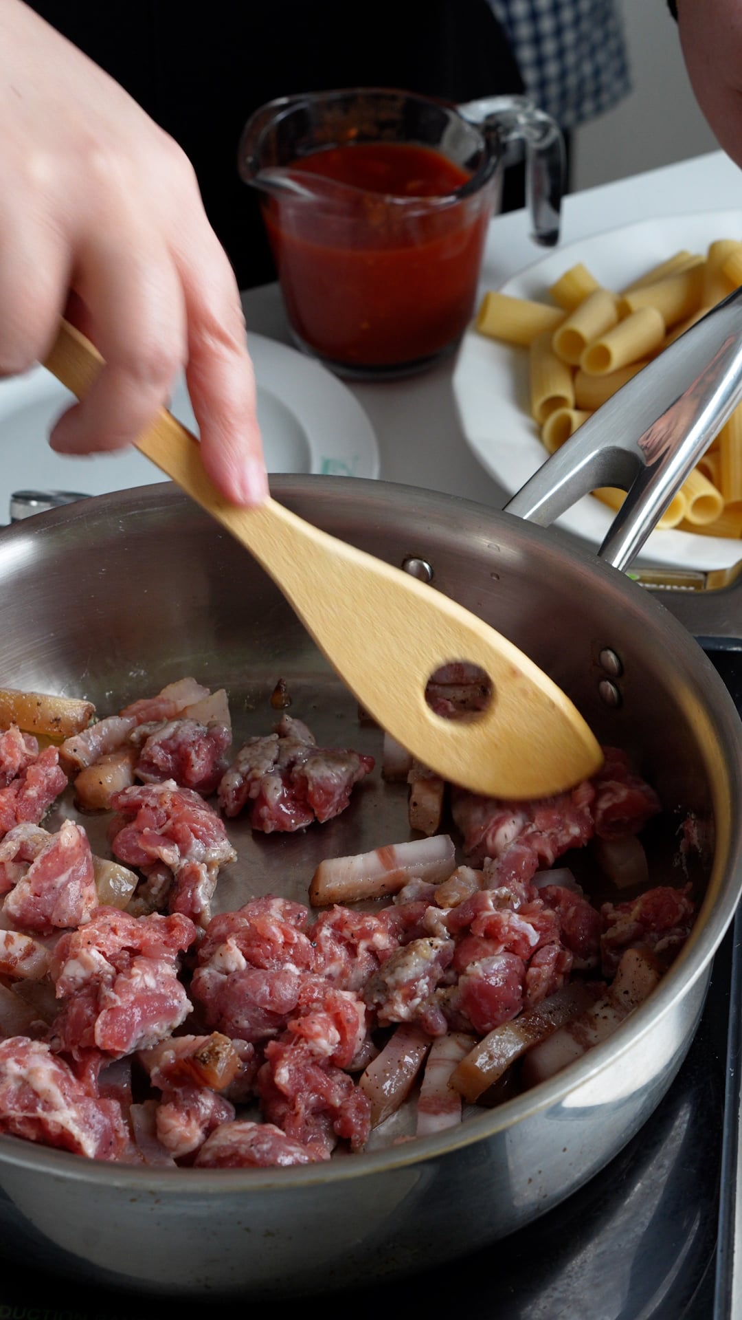 Guanciale and sausage in a pan being sautéed