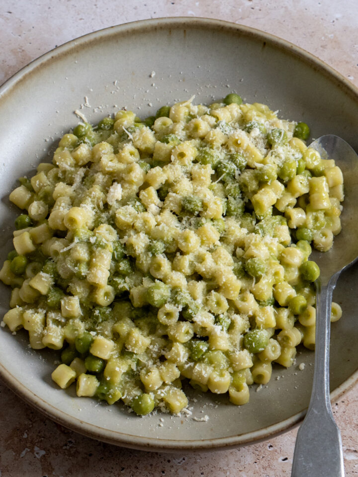 Pasta e piselli in a bowl with a spoon to the side