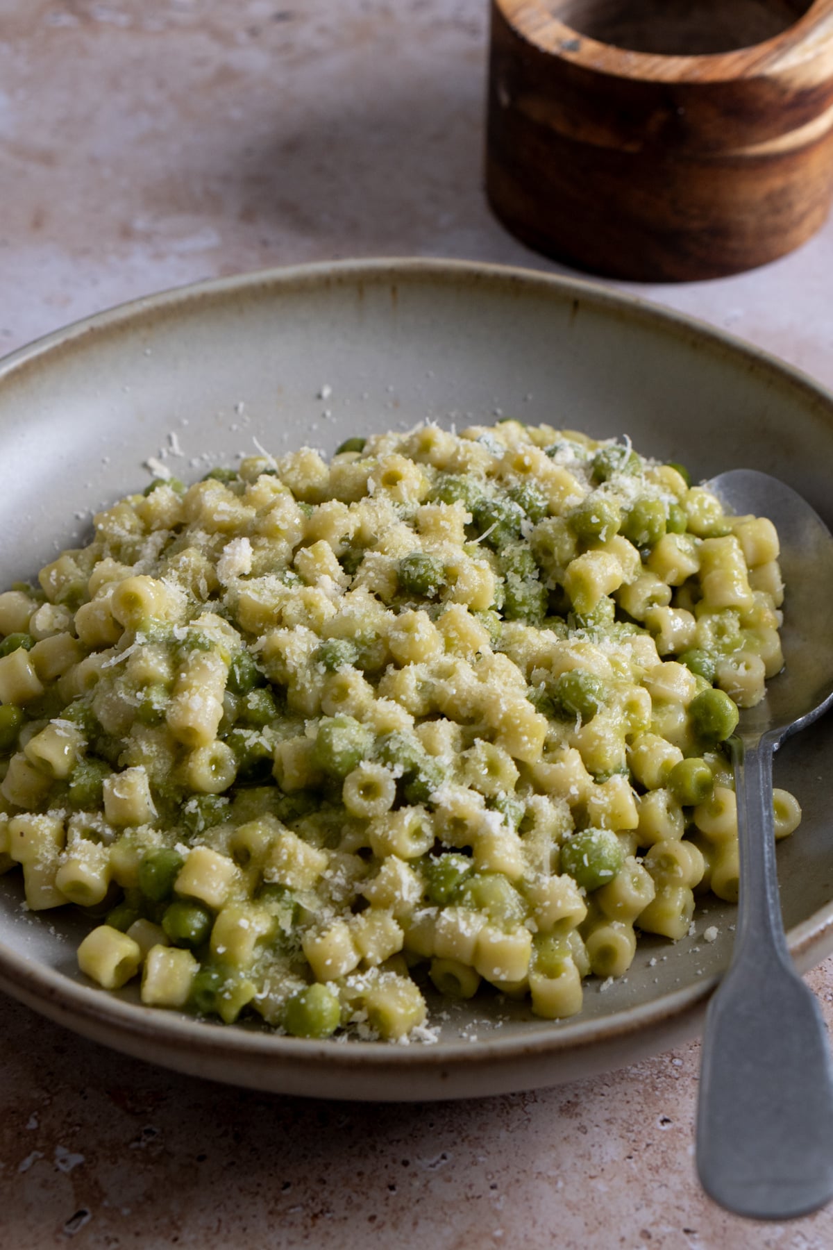 pasta e piselli in a bowl topped with grated parmigiano reggiano