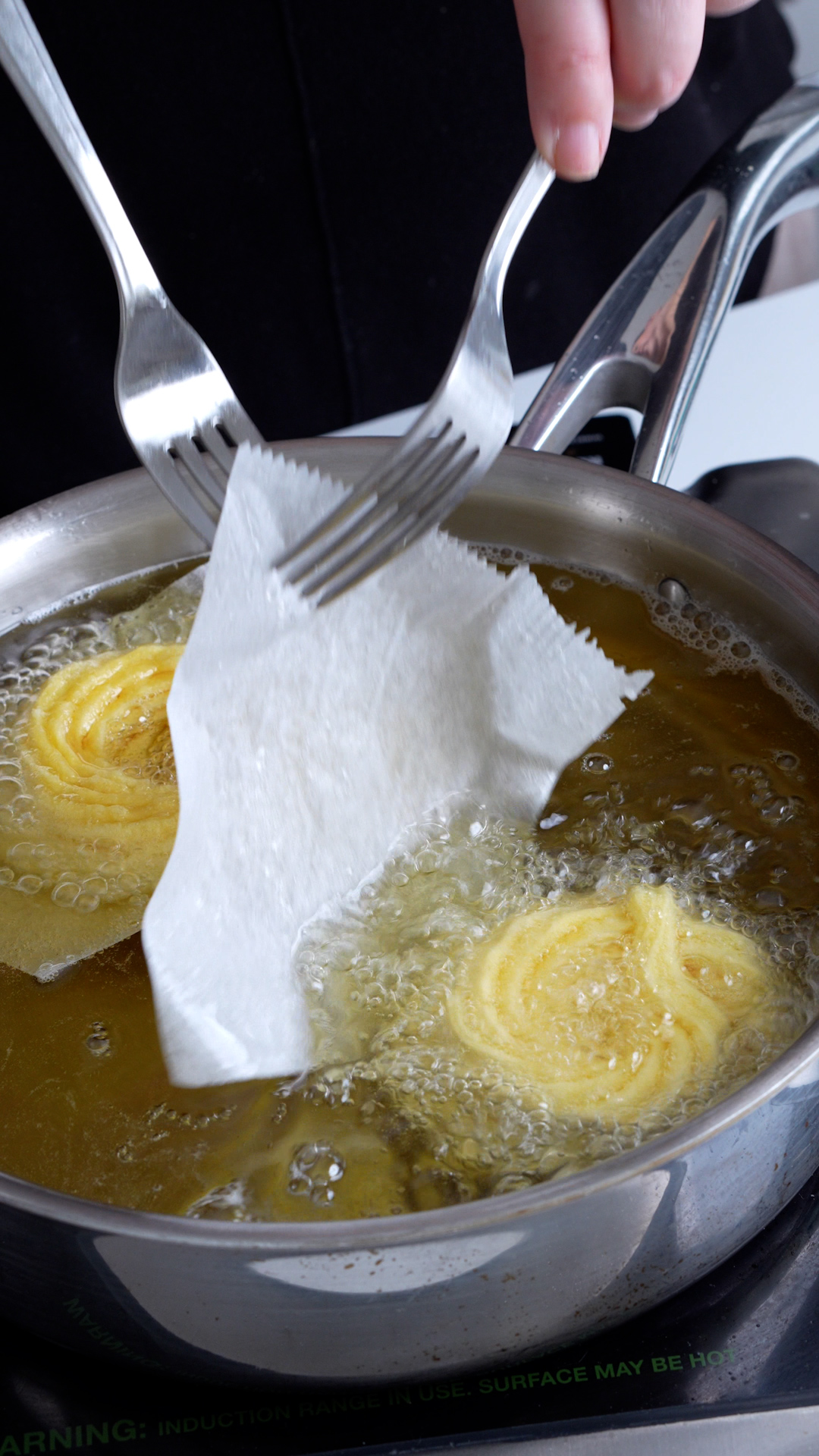 Zeppole being fried in a pan in oil
