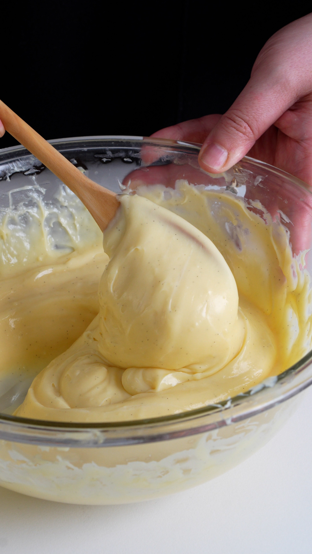 Pastry cream in a glass bowl being mixed with a spoon