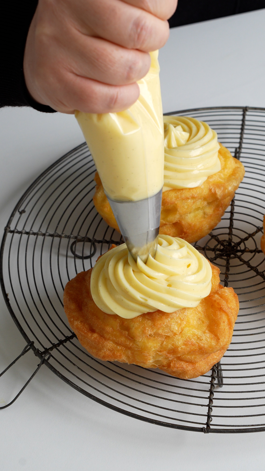 Pastry cream being piped onto zeppole