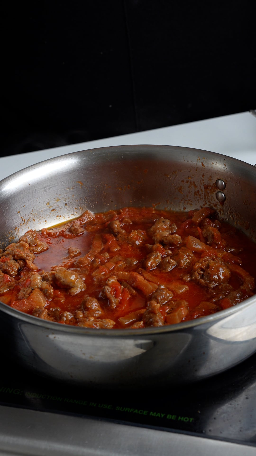 Sauce in a pan with tomatoes, guanciale and sausage