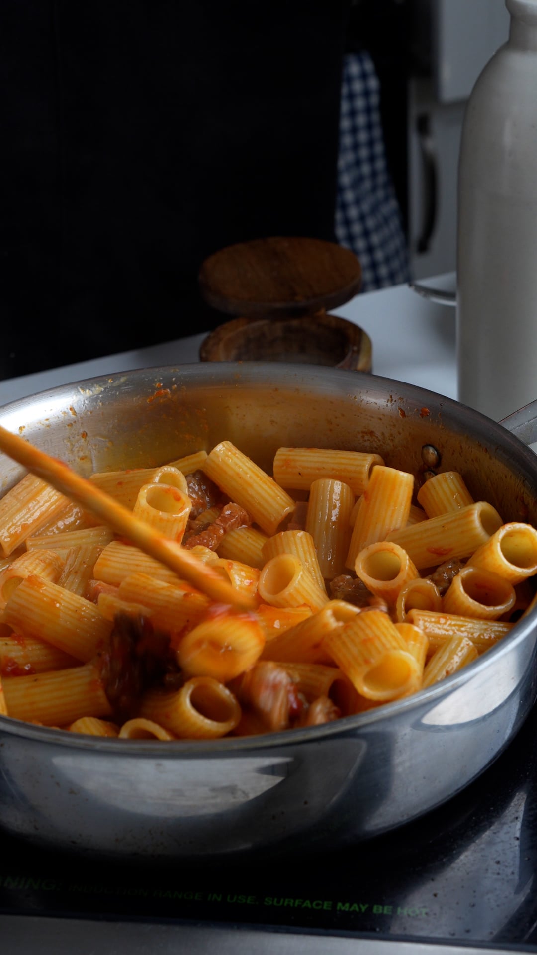 Rigatoni being mixed in a pan with sauce